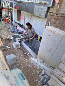 Mann vor einem Rohbau arbeitet mit Erde und Mauerwerk