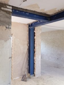 Blaue Stahlträgerstütze in einem Rohbau stützt Decke